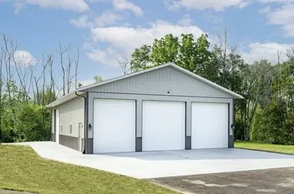 Completed gray pole barn with white overhead garage doors