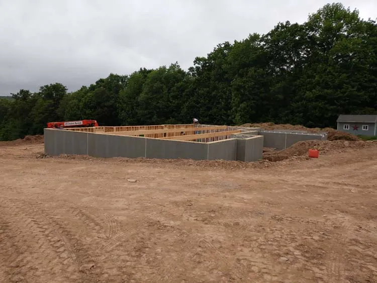 Superior Walls precast foundation panel being set by crane, with window and door openings already formed